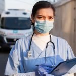 Young female NHS UK EMS doctor in front of healthcare ICU facility